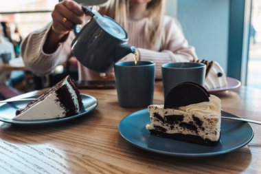 A girl in a cafe pours tea into cups. Beautiful cozy photo.