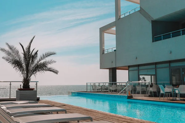 Summer outdoor swimming pool and sun loungers. In the hotel to rest. Seaview landscape.