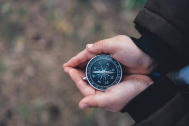 Navigation compass in hand. Travel and camping in forest. Finding path and direction.