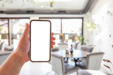 Mockup image of woman's hands holding white mobile phone with blank screen in cafe