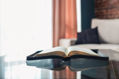 Open bible on table in living room, modern interior