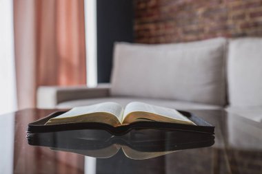 Open bible on table in living room, modern interior