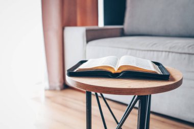 Open bible on table in living room, modern interior