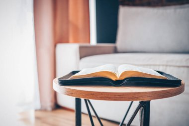 Open bible on table in living room, modern interior