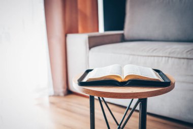 Open bible on table in living room, modern interior