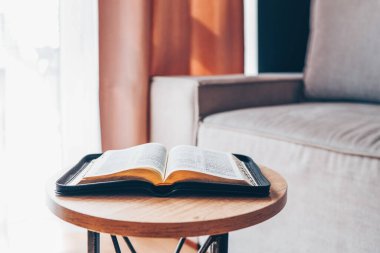 Open bible on table in living room, modern interior