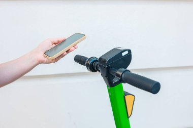 A man with a phone in his hands uses an application for an electric scooter