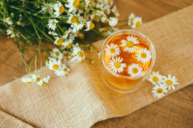 Çaydanlık ve çay bardağının yanında papatya çayı ve papatya çiçeği. Kırsal ya da kırsal arkaplan.