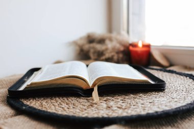 Open Holy Bible on a old wooden table and white wall background. Religion concept. Cozy warm photo