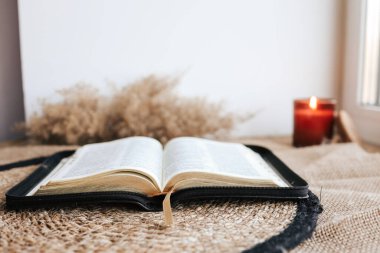 Open Holy Bible on a old wooden table and white wall background. Religion concept. Cozy warm photo