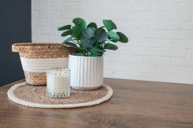 Home interior. Still life with detailes. Wicker basket with plants and candles on the kitchen table, the concept of cosiness. Close up.