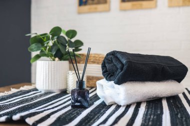 Spa treatment, aroma diffuser, candle and stack of towels, stylish bathroom interior.