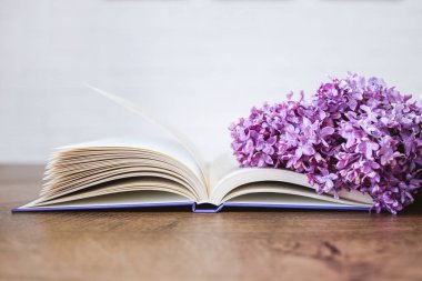 An open book with a lilac branch on the table. The postcard is beautiful. Good morning concept.