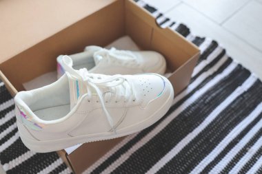 Women's sneakers in an open shoe box. Unpacking, top view.