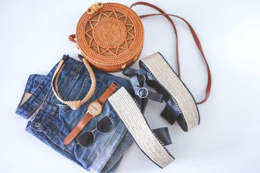 Women's summer clothes collage on white, flat lay. Woven sandals, rattan bag, watch, shorts, sunglasses top view.