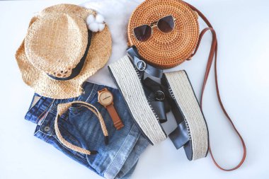 Women's summer clothes collage on white, flat lay. Woven sandals, rattan bag, watch, shorts, sunglasses top view.