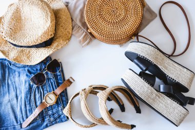 Women's summer clothes collage on white, flat lay. Woven sandals, rattan bag, watch, shorts, sunglasses top view.