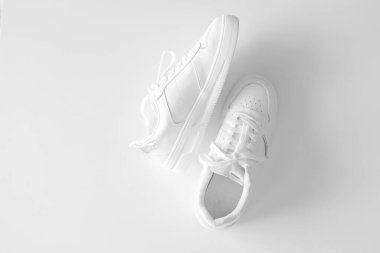 Beyaz arka planda beyaz kadın deri spor ayakkabıları düz yerde yatıyordu. Şık gençlik ayakkabıları, spor ayakkabıları, hakiki deri ayakkabılar. Minimalist ayakkabı mağazası reklamcılığı moda ayakkabısı arka planı