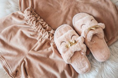 Home slippers and cozy pajamas on a fluffy white plaid