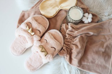 Home slippers and cozy pajamas on a fluffy white plaid