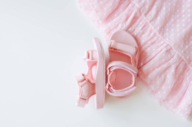 Pink children's sandals and dresses, top view.
