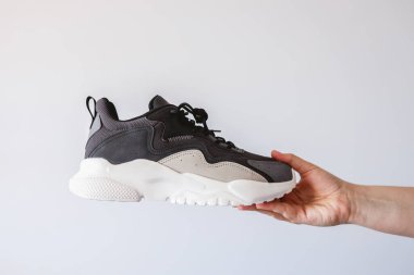 Stylish men's sneakers in hand on a white background.
