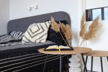 Open bible on wooden table in bedroom, scandinavian interior