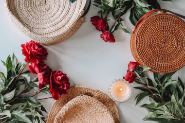 Flat lay set of summer accessories, wicker hat, bag, peonies, candle