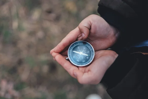 Navigation compass in hand. Travel and camping in forest. Finding path and direction.