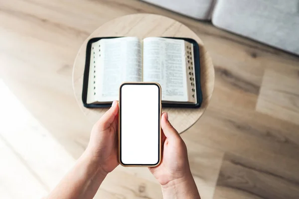 Woman hand hold and touch screen smart phone,cellphone in church over blurred bible holy and age book.