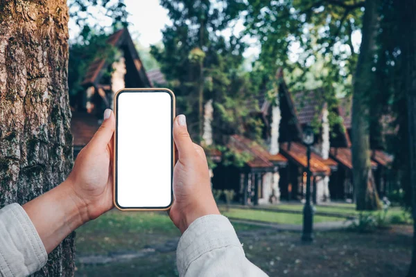 Hand with a phone in the background of a country house