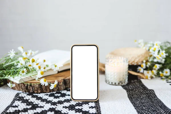Screen phone with isolated screen. Open book on the table with daisies
