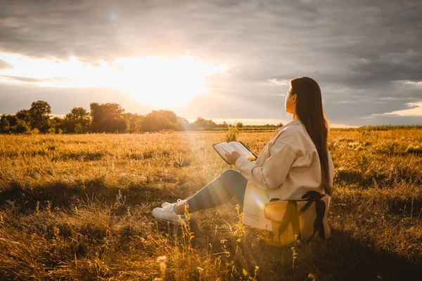 Christian woman holds bible in her hands. Reading the Holy Bible in a field during beautiful sunset. Concept for faith, spirituality and religion. Peace, hope