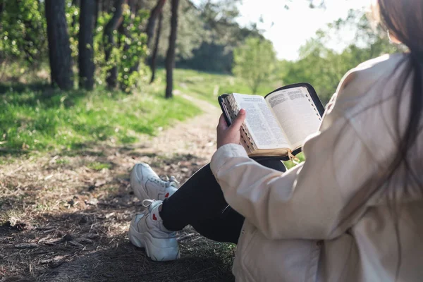 Christian woman holds bible in her hands. Reading the Holy Bible in a field during beautiful sunset. Concept for faith, spirituality and religion. Peace, hope