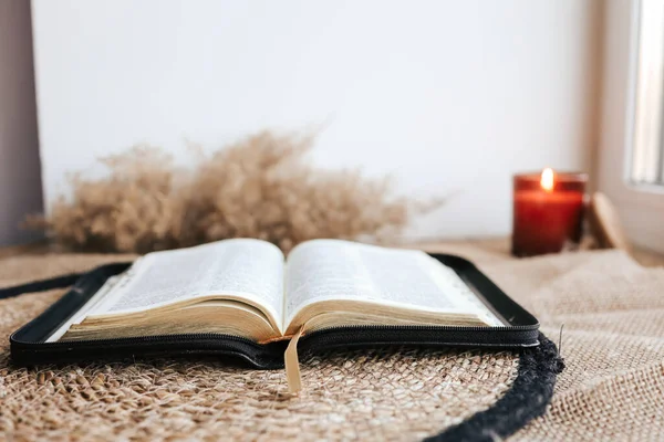 Open Holy Bible on a old wooden table and white wall background. Religion concept. Cozy warm photo