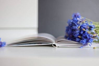 A bouquet of cornflowers and a book on the table
