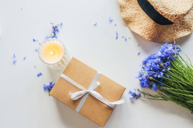 Set of summer things hat, cornflowers gift, candle flat lay