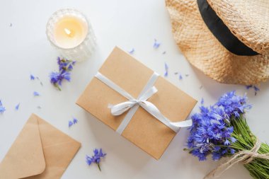 Set of summer things hat, cornflowers gift, candle flat lay