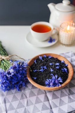 Black natural tea with cornflower petals on the table