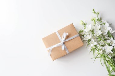 Cardboard gift box with a bow and flowers on a white background