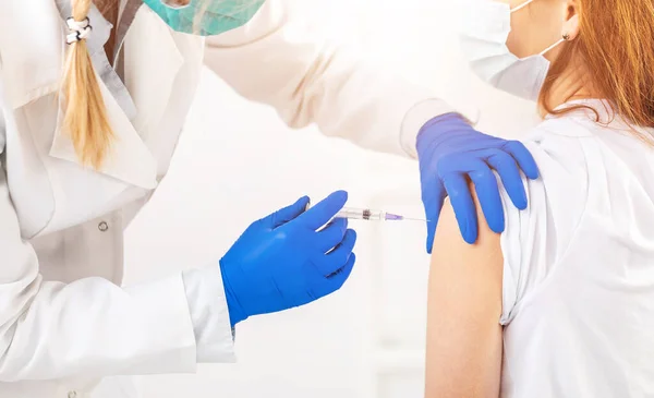 Doktor hastaya aşı enjekte ediyor.