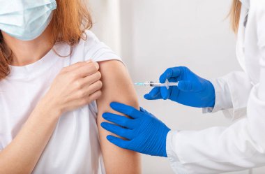 Eldivenli doktor hasta aşılıyor.