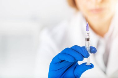 Doktor elinde aşıyla şırınga tutuyor.