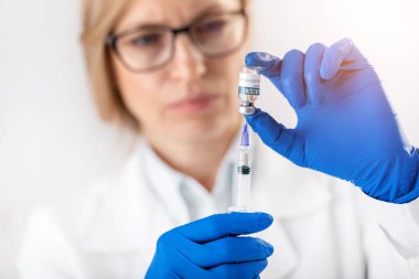 Aşı şişesi ve şırıngası olan doktor.