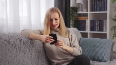 Evde akıllı telefon kullanan bir kadın.