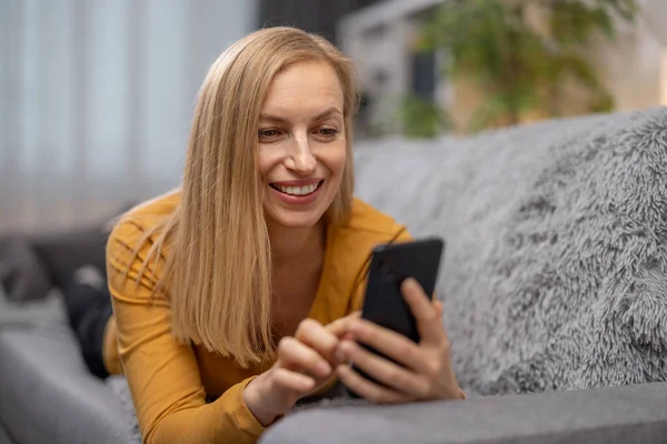 Kvinna som använder smartphone på soffan — Stockfoto
