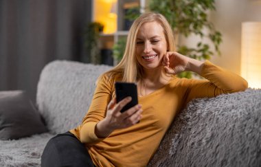 Kanepenin üzerinde telefon kullanan kadın