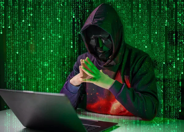 Хакер в маске с ноутбуком — стоковое фото
