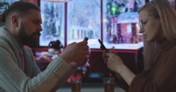 Pareja con teléfonos inteligentes en la cafetería — Vídeo de stock