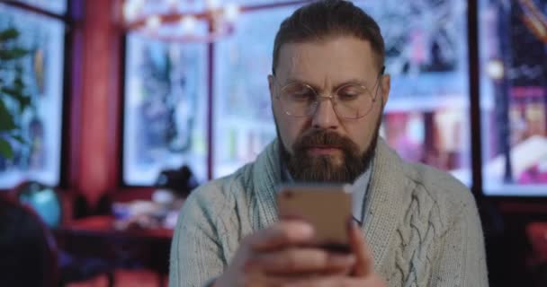 Человек, использующий смартфон в кафе — стоковое видео
